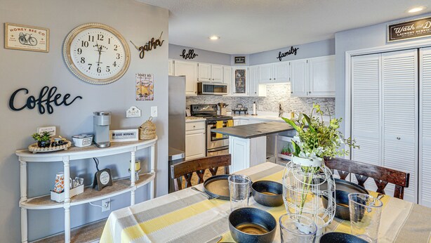 Una cocina moderna con armarios blancos, una isla central y un comedor con mantel a rayas.
