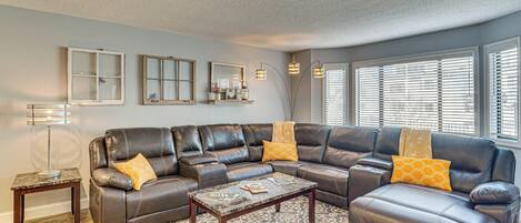 A living room with a sectional sofa, a coffee table, a patterned rug, and a floor lamp.