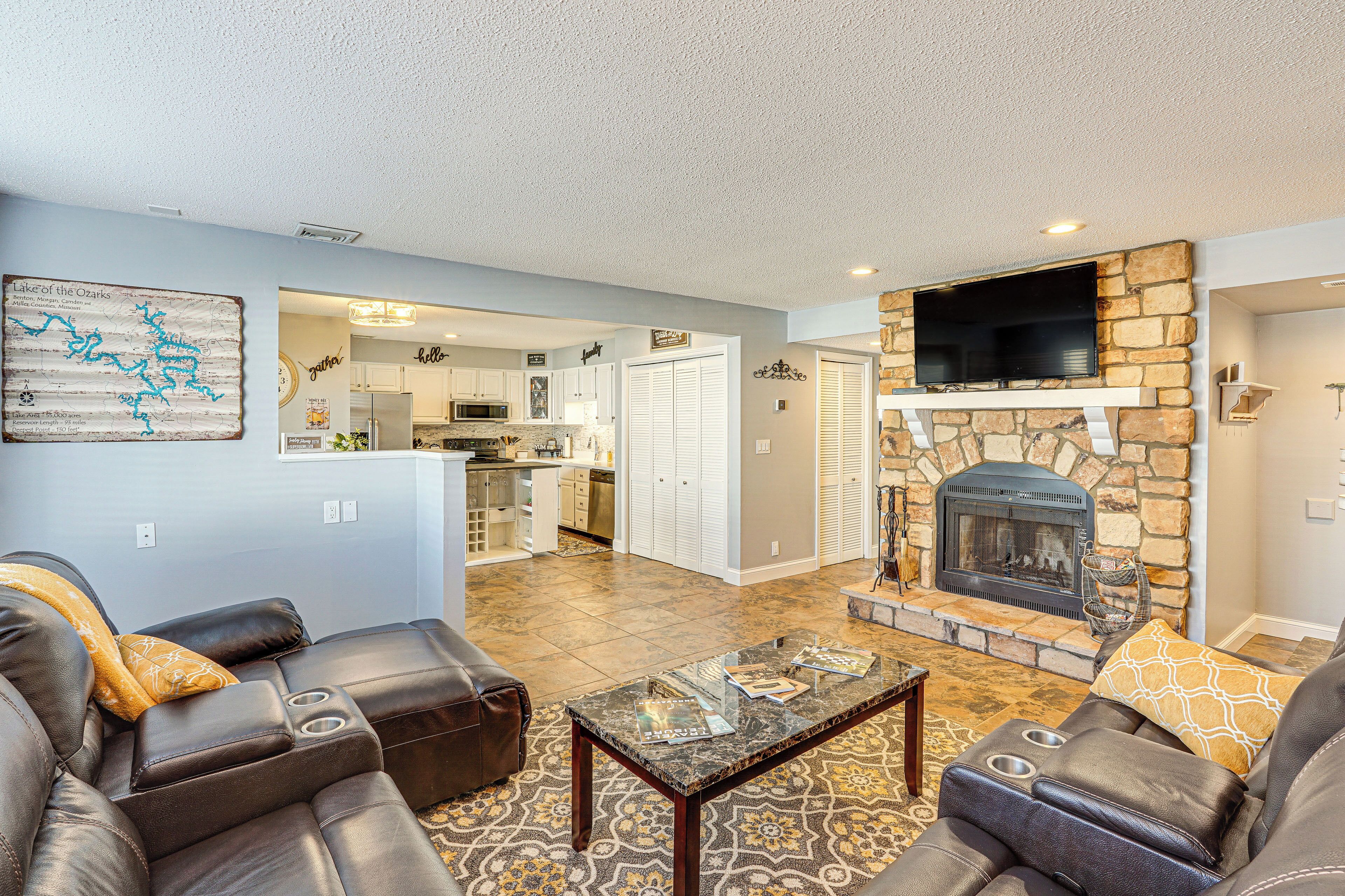 A modern living room with leather sofas, a glass coffee table, and a stone fireplace.