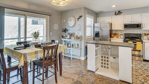 Una cocina con armarios blancos, una isla central y un comedor con mesa para cuatro.