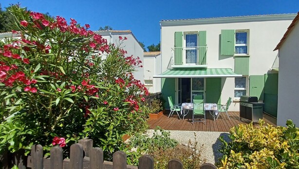 A courtyard with a wooden deck, a table with chairs, and a barbecue grill. - L'Escapade Charentaise, a quiet getaway with swimming pool (LA TREMBLADE)