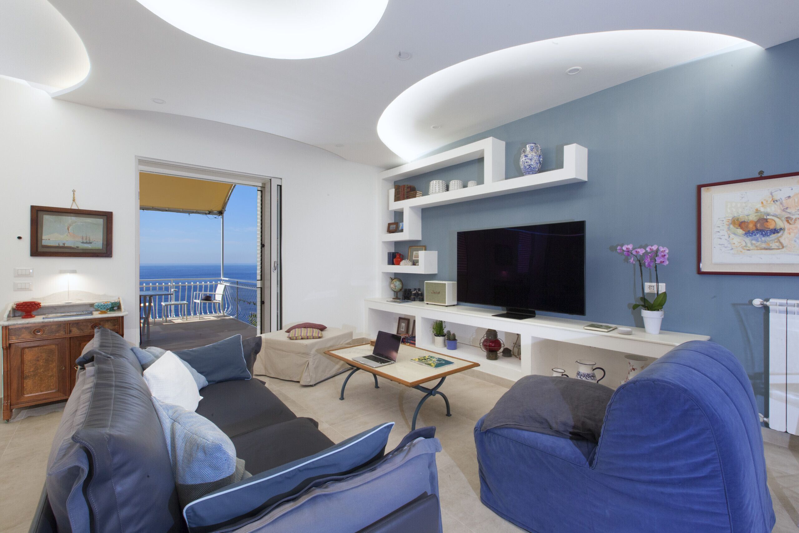 Un soggiorno moderno con balcone, televisione a schermo piatto e diversi oggetti decorativi.