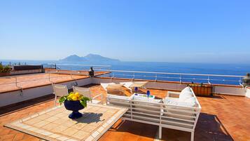 Una terrazza con tavolo, sedie e vista sul mare.