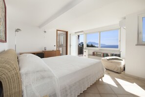 Una camera da letto con un letto, una cassettiera, uno specchio, una finestra con vista e una porta che dà su un'altra stanza.