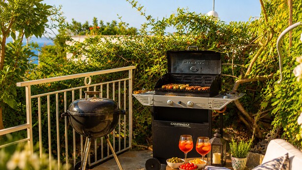 En grill med mat, en skottkärra och ett bord med drycker och snacks.
