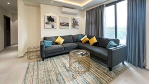 A modern living room with a sectional sofa, a round coffee table, and a large window with curtains.