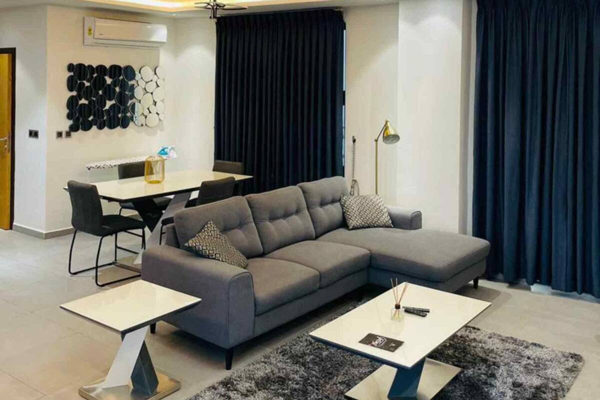 A modern living room with a sectional sofa, a coffee table, a rug, and a dining area with a table and chairs.