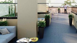 A modern outdoor balcony with a sofa, a small table with a vase, and potted plants.