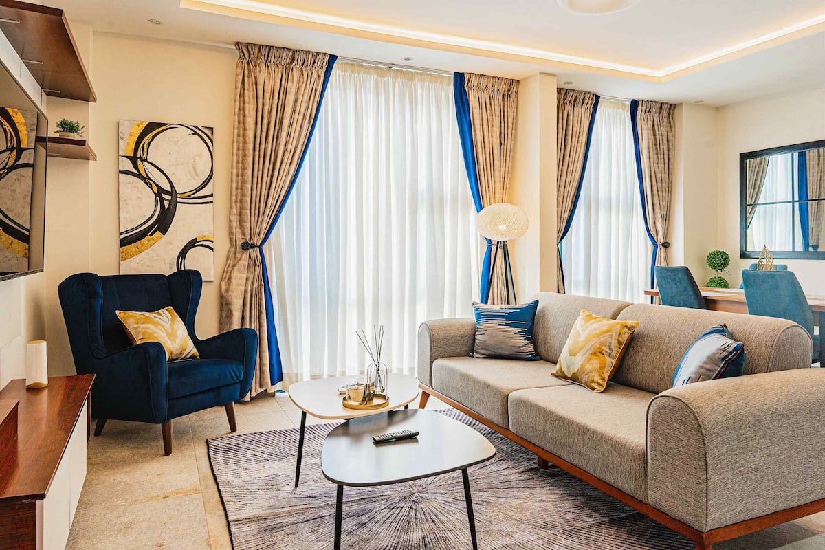 A modern living room with a sofa, armchair, coffee table, and a lamp.