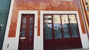Ein mehrstöckiges Gebäude mit Ziegelverkleidung, großen Fenstern und einem Balkon.