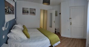 A bedroom with a bed, a mirror, a wardrobe, and artwork on the wall.