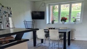 Cozinha ampla com área de refeições, piso de madeira e televisão na parede.