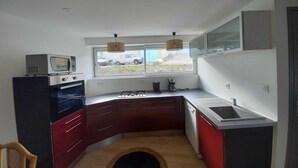 Cocina compacta con microondas, estufa y lavabo. Una ventana ofrece vistas al exterior.
