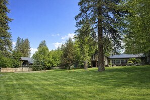 A house with a large lawn, surrounded by trees and a wooden fence.