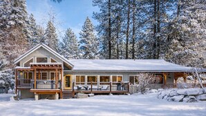 Een chalet met veranda, grote ramen en een overdekt terras.