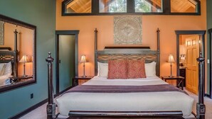 Un dormitorio con una cama grande, vigas de madera en el techo y un tragaluz.