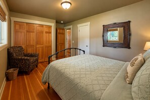 A bedroom with a bed, a chair, a wardrobe, and a mirror. - Riverside Cabin-River, Hot Tub, WIFI, Dogs OK (Leavenworth)