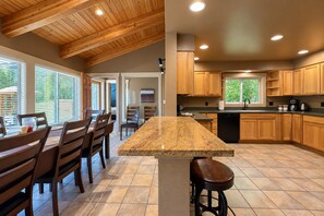 A spacious kitchen with wooden cabinets, a granite countertop, and a dining area with chairs.
