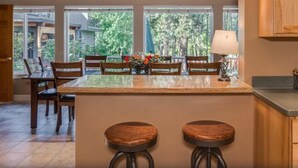 Een keuken met een centraal eiland, houten stoelen en een eettafel.