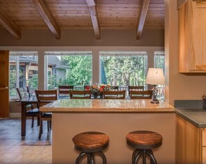 A kitchen with a central island, wooden chairs, and a dining table. - Riverside Cabin-River, Hot Tub, WIFI, Dogs OK (Leavenworth)