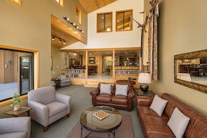A spacious living area with leather sofas, a glass coffee table, and a bookshelf.