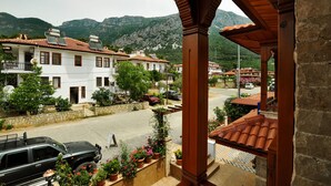 Vista de una calle con edificios, un coche aparcado y montañas al fondo.