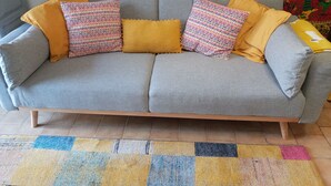 A grey sofa with patterned cushions and a colorful rug. - Rustic cottage in the heart of the Bastides, Lot-et-Garonne.  Perfect for 2! (Montauriol)