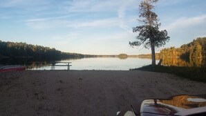 Un terrain de camping au bord du lac, équipé d’une table de pique-nique et d’un canoë.
