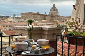 A table set with plates, glasses, and a vase on a balcony overlooking a cityscape with historic buildings. - Pauline's View, una splendida finestra sulle bellezze della Roma antica. (Rome)