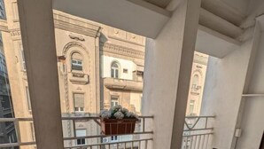 A balcony with a glass table and two chairs, a flower pot, and a view of neighboring buildings. - Montana Hotel (Cairo)
