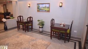 A dining area with a table and four chairs, a potted plant, and a framed landscape painting on the wall. - Montana Hotel (Cairo)