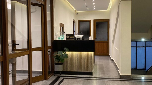 A modern reception area with a reception desk, a potted plant, and a sign indicating the reception. - Montana Hotel (Cairo)