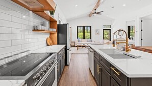 A modern kitchen with a central island, built-in oven, and a dining area with a sofa and coffee table.