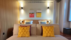 A modern bedroom with a sofa bed, two wall-mounted lights, and abstract art on the wall. - Fervença Apartments - Sabor (Vila Nova de Gaia)