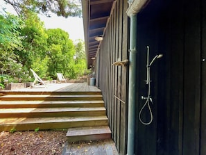 A wooden staircase leading to a covered outdoor area with a shower.