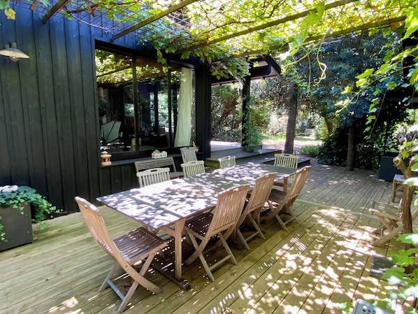 Relax in a serene outdoor space surrounded by lush greenery and trees, featuring a dining table and bar area.