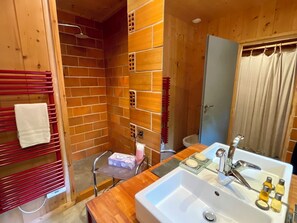 Bathroom features a large sink, modern faucet, and a shower area with a glass door.