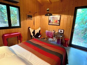 Ein Zimmer aus Holz mit einem Bett, einem Schreibtisch, einem Stuhl und einem Fenster.