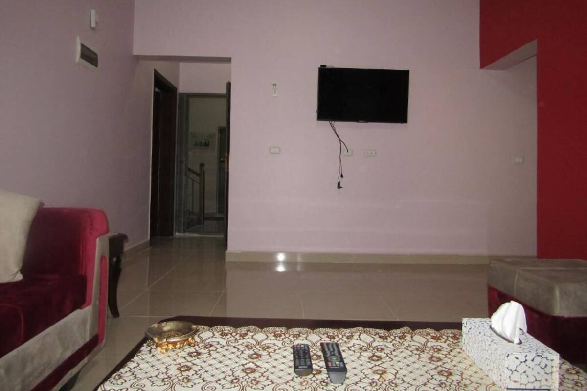 A living room with a sofa, a television mounted on the wall, and a patterned rug.