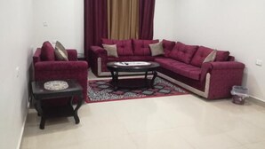 A living room with a sectional sofa, a small side table, and a patterned rug. - Petra Crystal hotel (Wadi Musa)