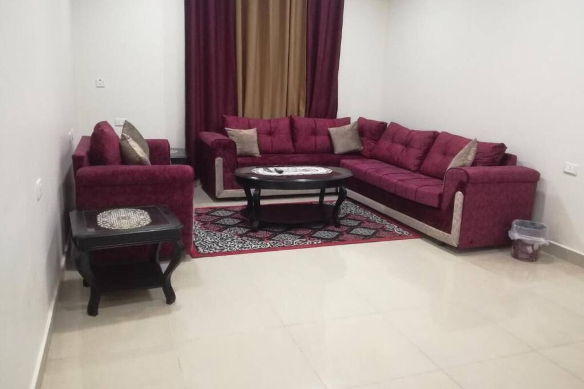 A living room with a sectional sofa, a small side table, and a patterned rug.