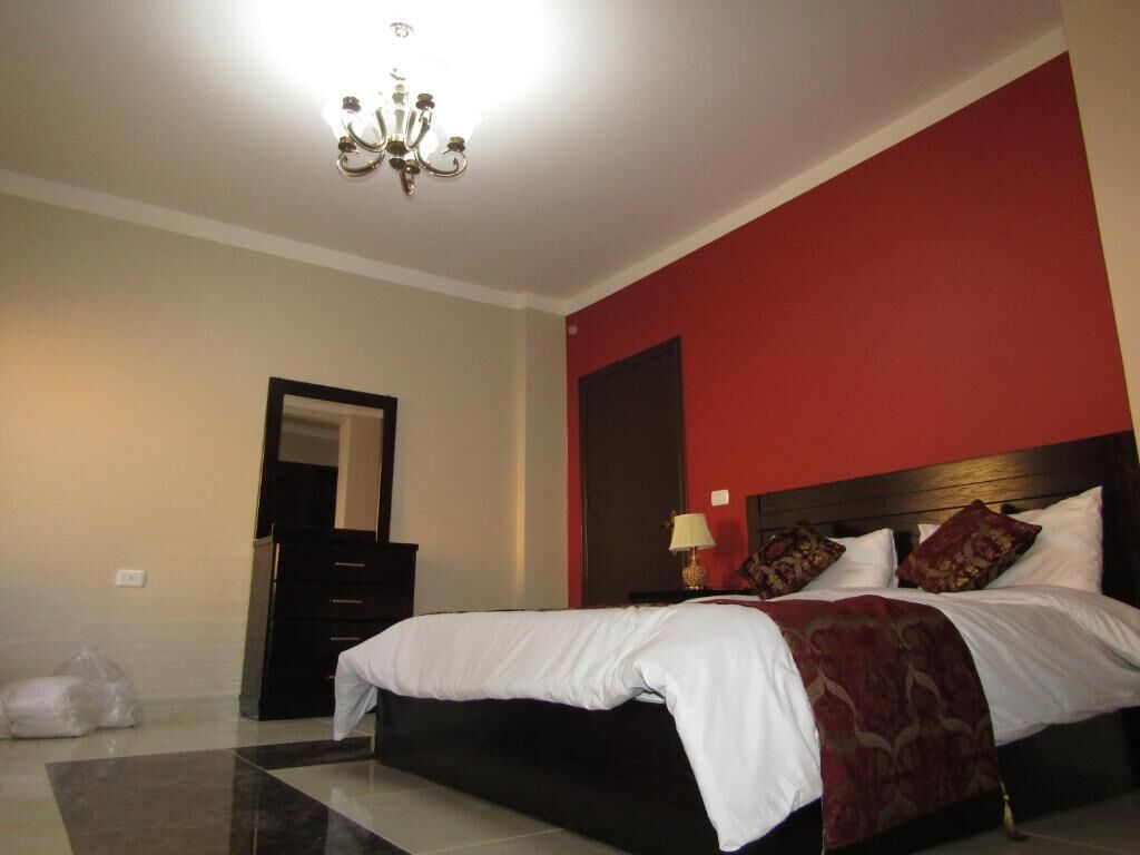 Une chambre à coucher avec un lit, une commode, un miroir et un lustre.