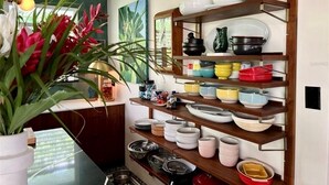 Een keuken met houten planken vol servies en een bloempot.