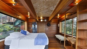 A modern bedroom with a large bed, wooden walls, and large windows. - Cap Ferrat Boutique Hotel (Búzios)