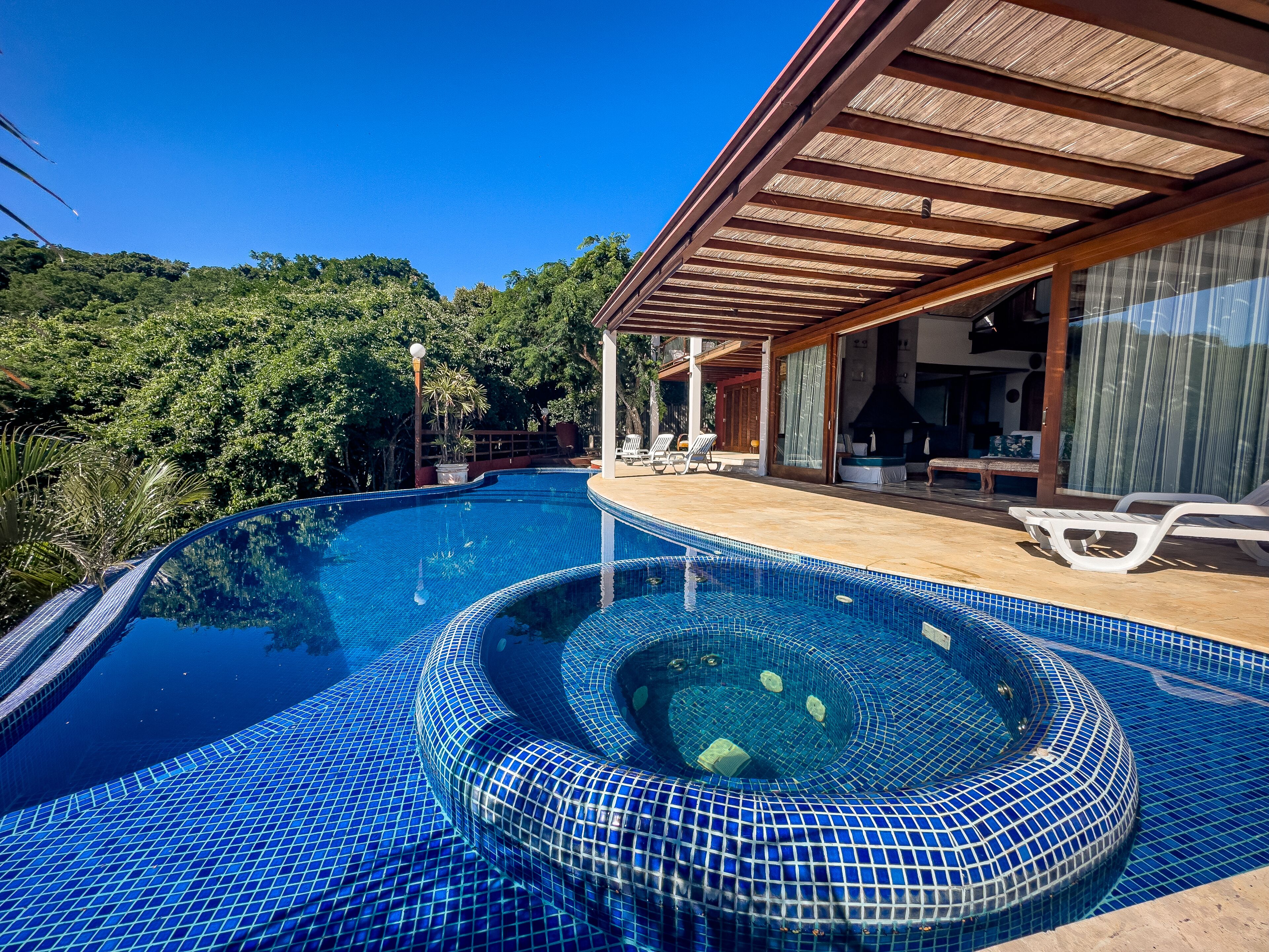 Una piscina al aire libre, sombrillas, sillones reclinables de piscina