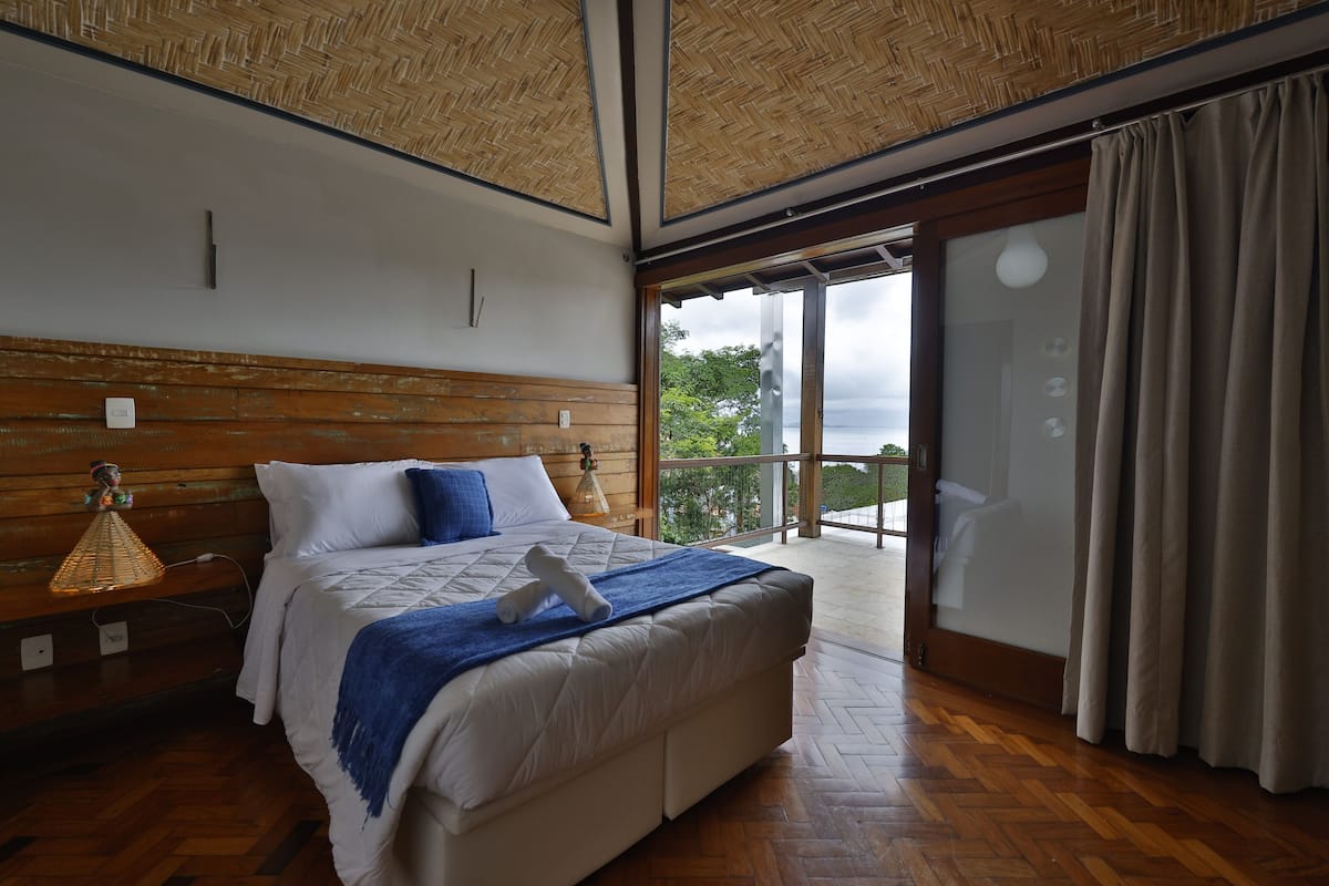 A bedroom with a large bed, wooden headboard, and a view of the outdoors through a sliding glass door.