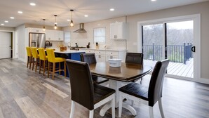 A modern kitchen with white cabinets, a central island, and a dining area with yellow chairs.