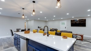 A modern kitchen with a central island, built-in appliances, and pendant lighting.
