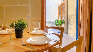 A dining table set with plates, cutlery, and wine glasses, with potted plants on the table. - Stay inside the walls of Gozo Cittadella fortress (Ir-Rabat Għawdex)