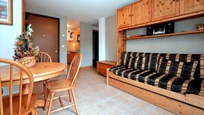 Ein gemütliches Wohnzimmer mit einem Holzesstisch, Stühlen, einem Karosode und Holzkästen über der Couch.